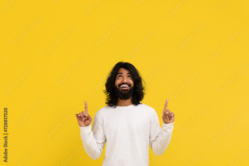 Amazed excited millennial indian guy pointing up at copy space Amazed excited millennial indian guy pointing up at copy space