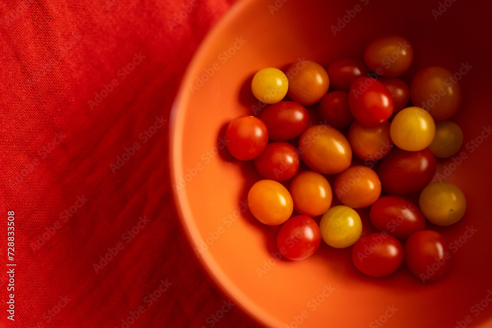Modern orange bowl with red cherry tomatoes from above Modern orange bowl with red cherry tomatoes from above