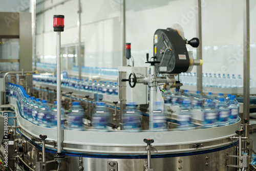 Blurry motion of production line with group of capped plastic bottles with filtered still or carbonated mineral water or some other drink