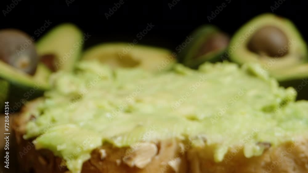 The knife spreads the green avocado flesh on a slice of white bread. Dolly slider extreme close-up. The knife spreads the green avocado flesh on a slice of white bread. Dolly slider extreme close-up.