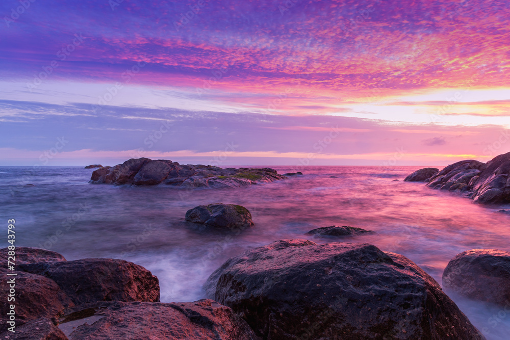 Obraz premium Twilight sunset sky over the ocean on beach with large rocks. Long exposure. Porto, Portugal