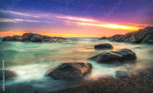 Purple sunset over the ocean on beach with large rocks. Long exposure. Porto, Portugal