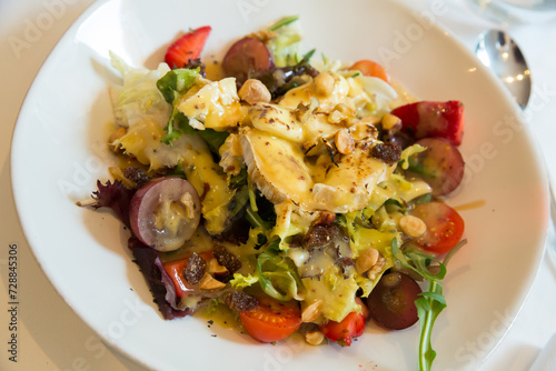 Salad with goat cheese, cherry tomatoes, arugula, nuts and raisins. High quality photo