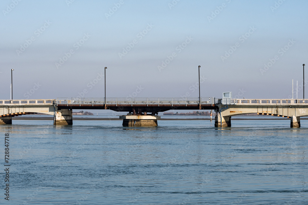 Grado, Italy - January 28th, 2024: Swing bridge at the entrance to the city Gradese seen from the final part of the Mandracchio port during a foggy day.