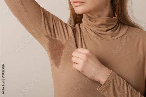  Close up image of woman in beige cotton turtleneck with sweat patch under armpit