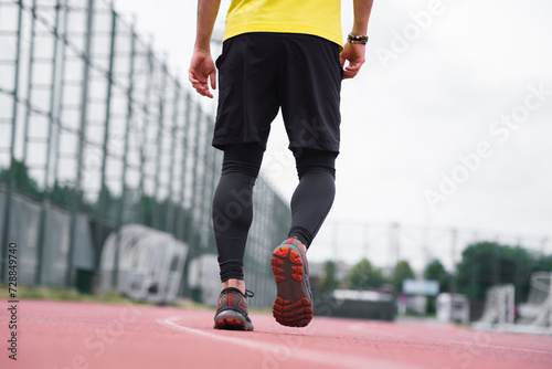 close up Dynamic backside view of a man in comfortable activewear run and jog on the track stadium, active and healthy lifestyle sports arena in the town park.
