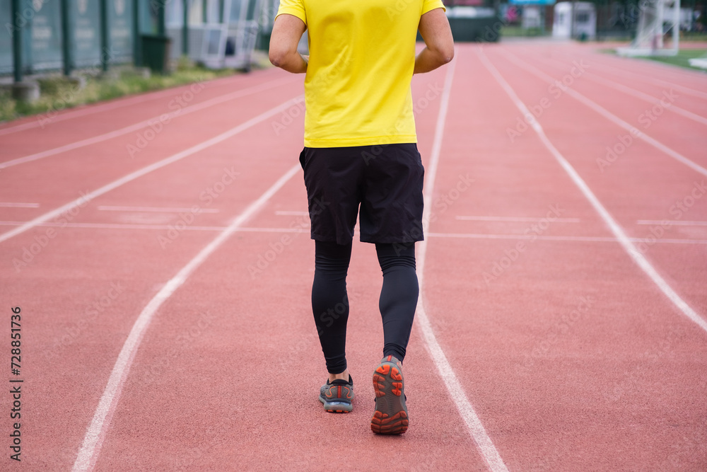man in activewear energetically running and jogging on the stadium track, active and healthy lifestyle on a contemporary sports arena in the town park