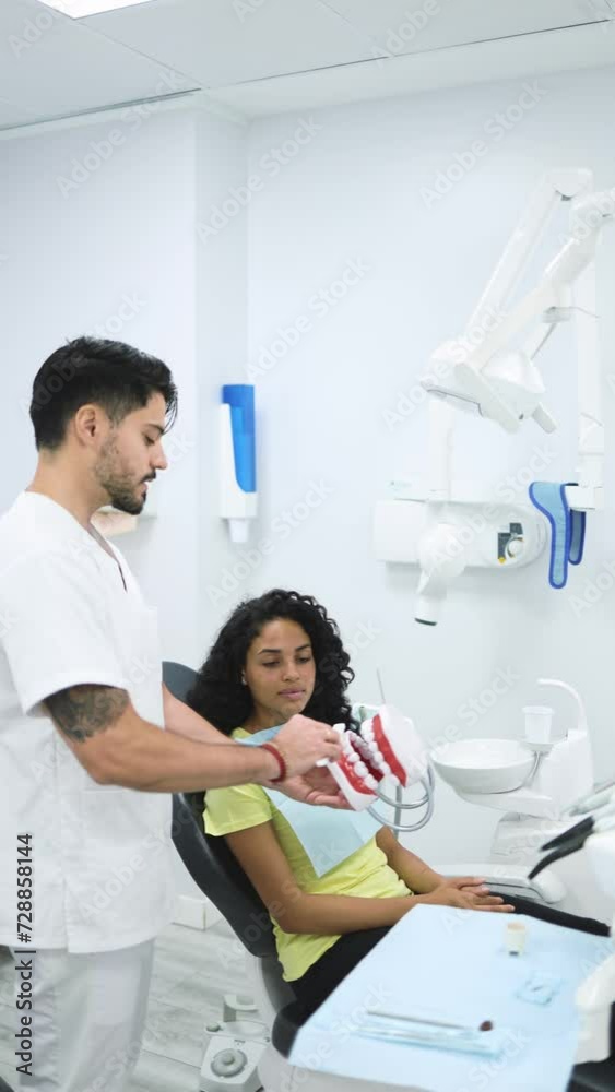 Vertical video of a male dentist showing how to correctly brush his patient's teeth with a jaw model in a modern dental clinic. Dentist scrubbing jaw model in hand with toothbrush Vertical video of a male dentist showing how to correctly brush his patient's teeth with a jaw model in a modern dental clinic. Dentist scrubbing jaw model in hand with toothbrush