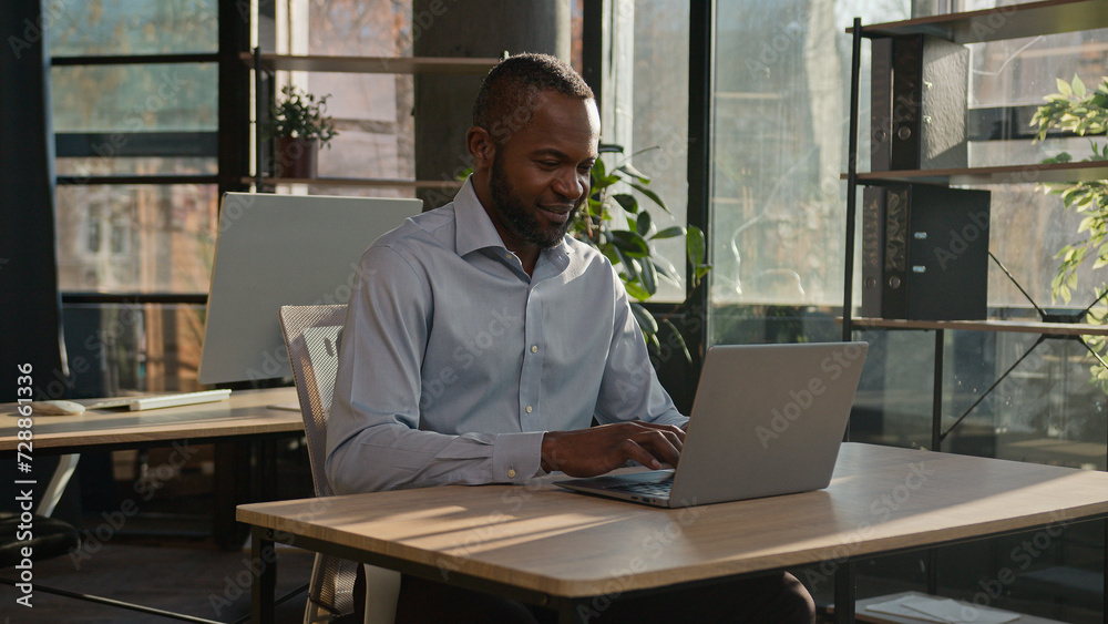 Mature senior businessman middle-aged specialist entrepreneur business owner African American man sit at sunny daylight office indoor company working remote with laptop computer typing email online Mature senior businessman middle-aged specialist entrepreneur business owner African American man sit at sunny daylight office indoor company working remote with laptop computer typing email online