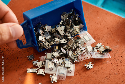 cropped view of professional technician with plastic box of different spare parts in repair workshop photo