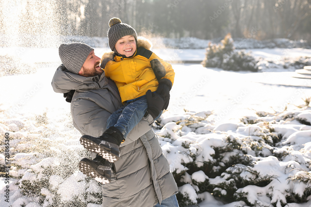 Family portrait of happy father and his son in sunny snowy park. Space for text