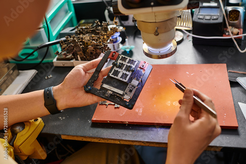 cropped view of professional technician examining shipset of electronic gadget in repair workshop photo