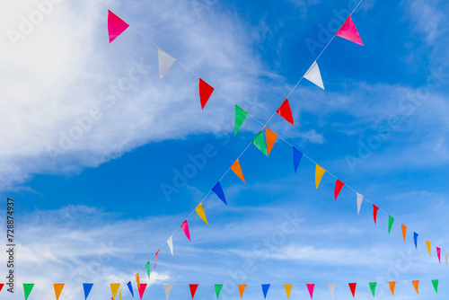 Colourful flag waving in the air on sky, Multicolour of pennant flags (Orange, Blue, Yellow, Red, White and Green) hanging on the rope under sky and clouds background, Free copy space for your text.