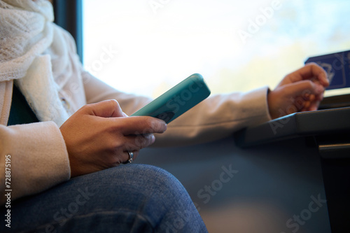 Close-up female hand holding smartphone  checking mobile app  planning route while travelling by comfortable city train