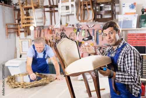 Professional furniture restorer in process of renovation vintage chair in workshop