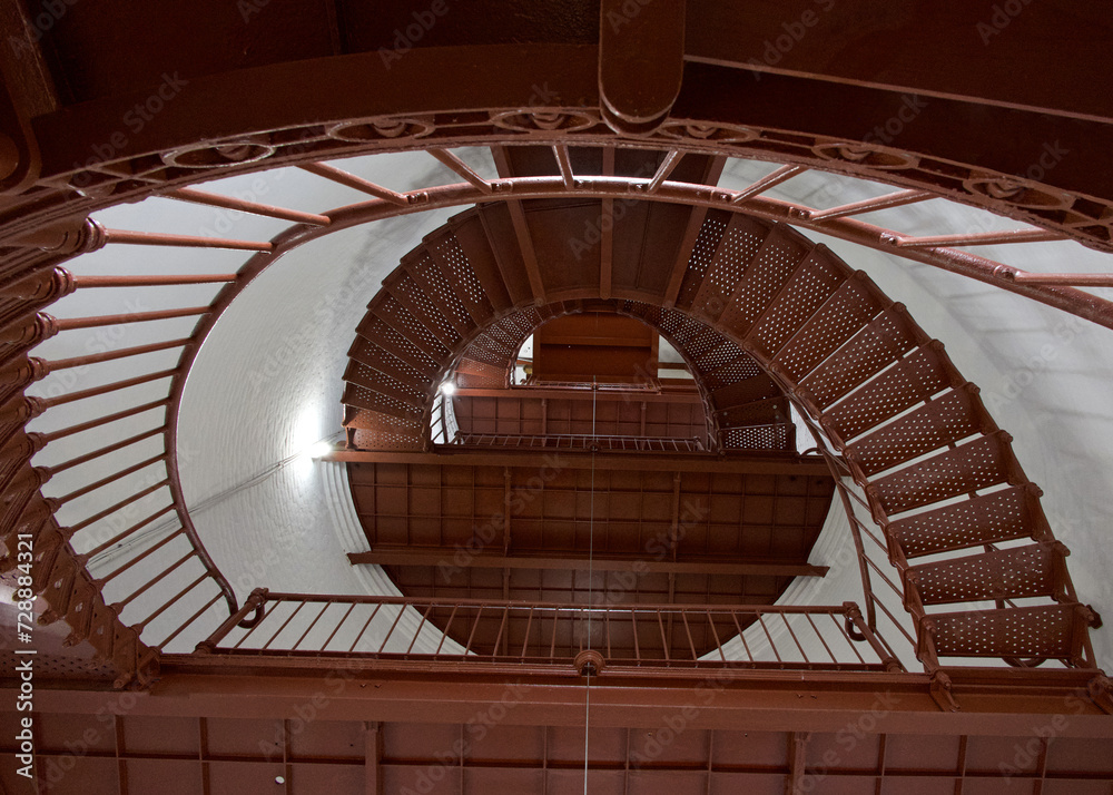 Obraz premium Red spiral staircase inside old lighthouse, view from bottom looking up towards the light.