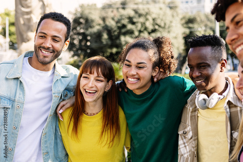 Happy multiracial young group of people hugging each other laughing at city. Millennial diverse friends from different cultures bonding enjoying free time on summer vacation. Youth community concept. #728884957