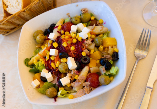 Traditional Mediterranean tuna salad with greens, grated carrot and beet, white asparagus, pickled olives, tomatoes, corn, sweet peach and feta cheese