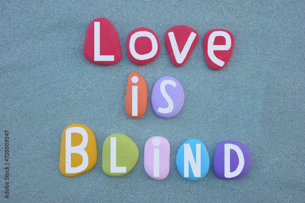 Obraz premium Love is blind, creative message composed with hand painted multi colored stone letters over green sand