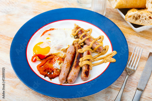 Healthy breakfast of scrambled eggs with sausages and tomatoes