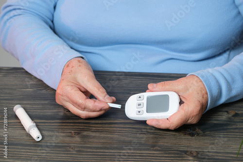 unrecognizable older woman using a blood sugar measuring machine