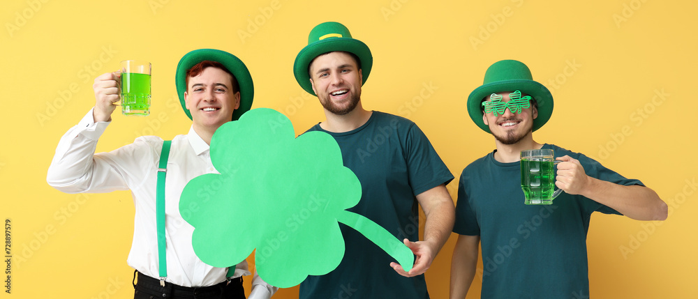 Happy young men in leprechaun's hats, with beer and clover on yellow background. St. Patrick's Day celebration Happy young men in leprechaun's hats, with beer and clover on yellow background. St. Patrick's Day celebration