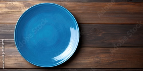 Blue plate on wooden background with empty space for design.