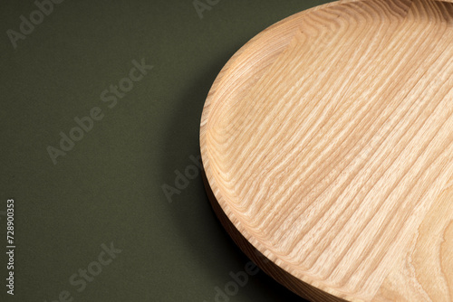 Wooden flat plates on a dark green background. The concept of ecological tableware. Products for modern kitchen. Natural harmony: wooden plates in an eco-friendly kitchen. Warm lamp shades.