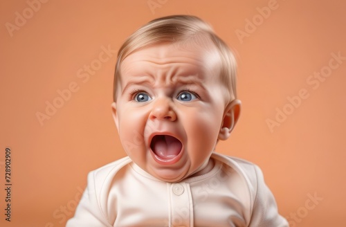 Close-up on small Caucasian boy toddler crying loudly against beige backdrop in need for baby care