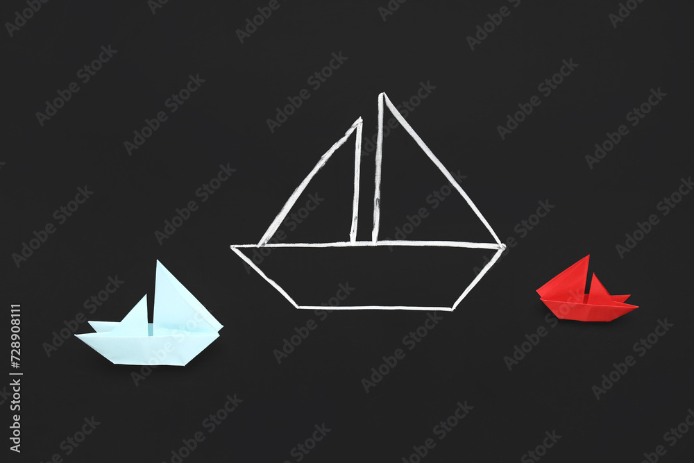 Drawn and colorful paper boats on black chalkboard Drawn and colorful paper boats on black chalkboard
