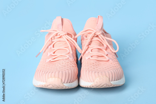 Stylish pink sneakers on blue background