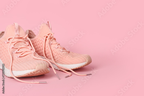 Stylish pink sneakers on color background