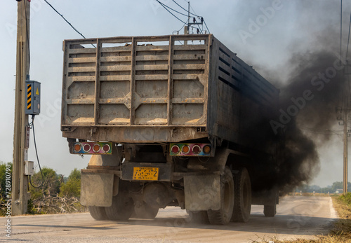 A loaded truck travels on the road with thick black smoke from the exhaust