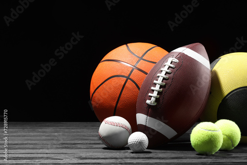 Many different sport balls on dark wooden table against black background, space for text © New Africa
