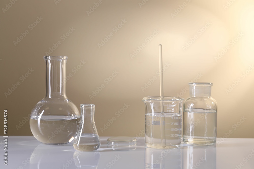 Laboratory analysis. Different glassware on table against beige background Laboratory analysis. Different glassware on table against beige background