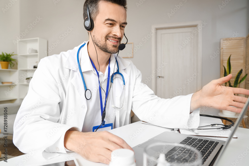 Handsome doctor in headset video chatting with patient on laptop at home office Handsome doctor in headset video chatting with patient on laptop at home office