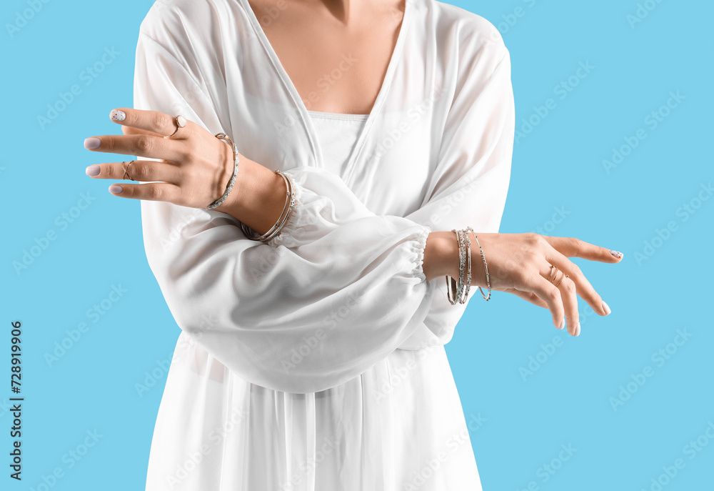 Beautiful young woman in white dress with rings and bracelets on blue background Beautiful young woman in white dress with rings and bracelets on blue background