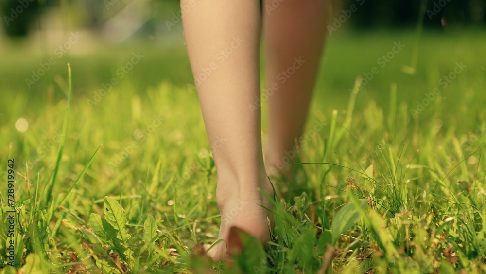 Baby go barefoot on green grass in park. Child feet walking in summer on green grass, slow motion. Healthy baby go in nature, active game. Happy family, children happiness. Little bare legged kid