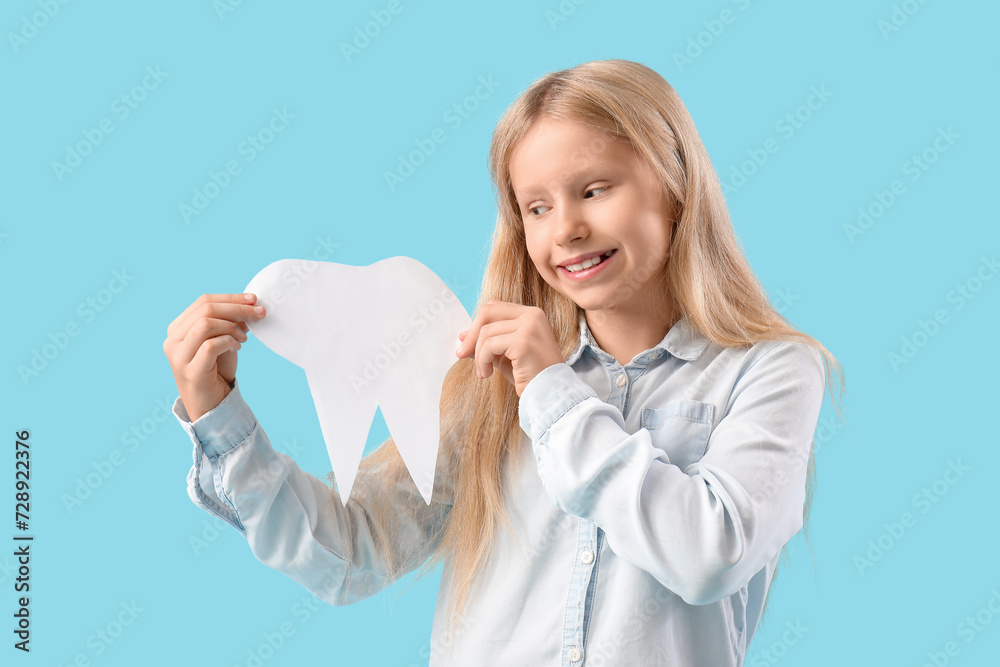 Happy little girl with healthy teeth and paper tooth on blue background Happy little girl with healthy teeth and paper tooth on blue background