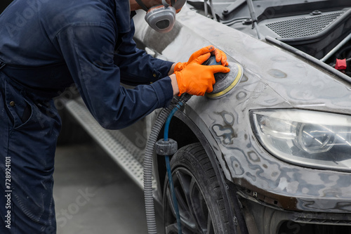 A mechanic sands the putty on a car body with a machine. Repair after an accident.  © Михаил Решетников