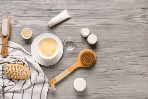 Composition with different cosmetic products and massage brushes on grey wooden background