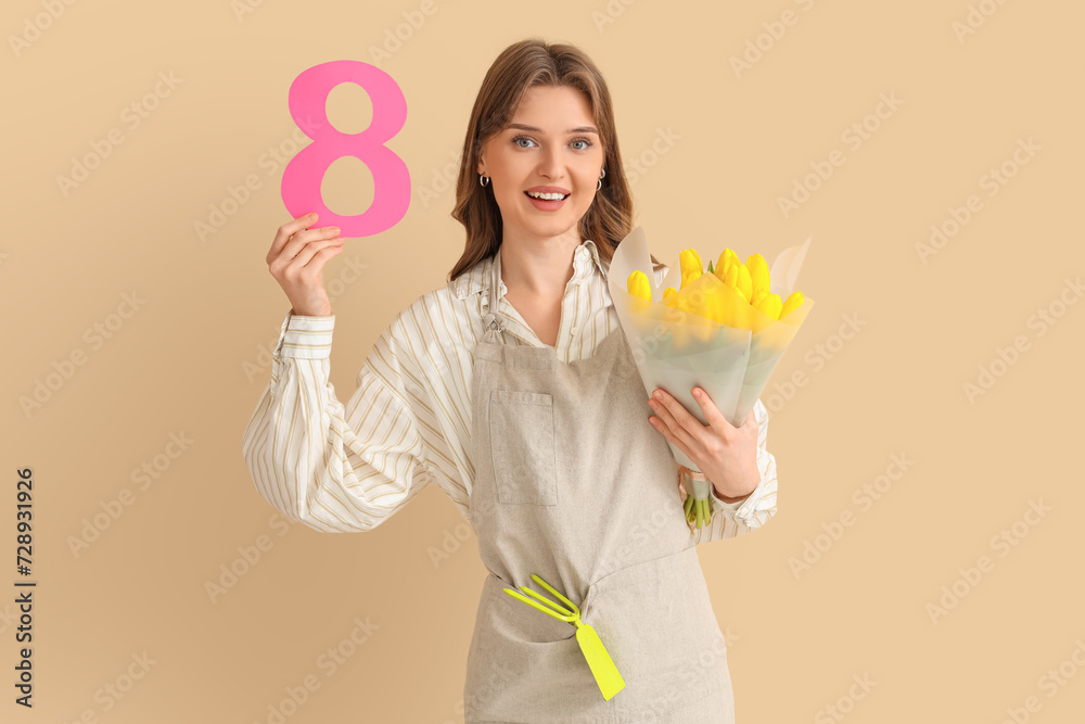 Young female gardener with bouquet of yellow tulips and paper figure 8 on beige background. International Women's Day celebration Young female gardener with bouquet of yellow tulips and paper figure 8 on beige background. International Women's Day celebration