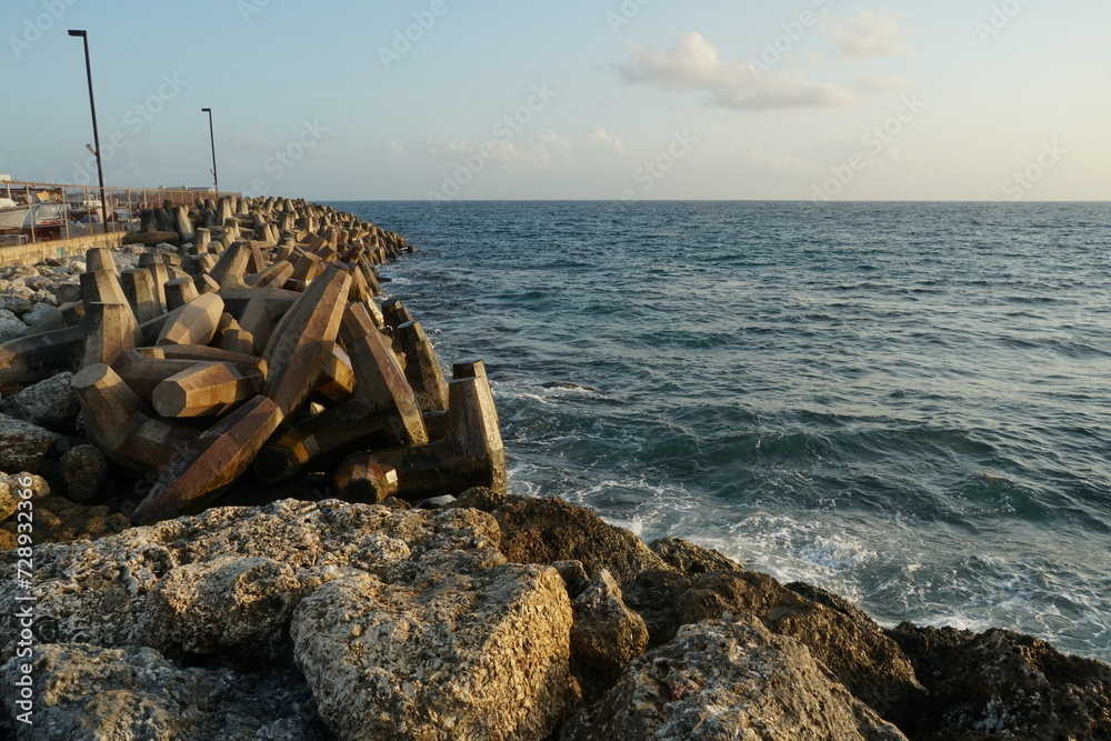 View on concrete, artificial, processed breakwater stones piled up in wave breaker to protect Port of Bridgetown, Barbados from waves of Caribbean Sea. In forward is stone wall.