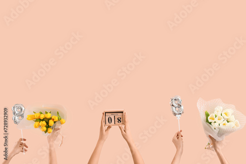Female hands with balloons in shape of figure 8, calendar and bouquets of tulips on beige background. International Women's Day celebration