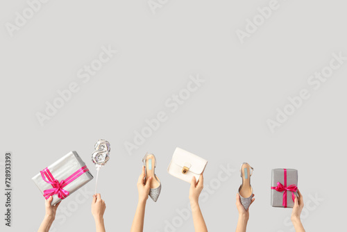 Female hands with handbag, gift boxes and high heel shoes on white background. International Women's Day celebration