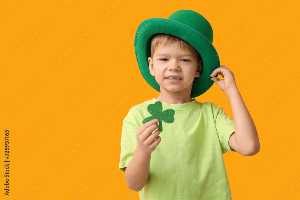 Cute little boy in leprechaun hat with clover on yellow background. St. Patrick's Day celebration Cute little boy in leprechaun hat with clover on yellow background. St. Patrick's Day celebration