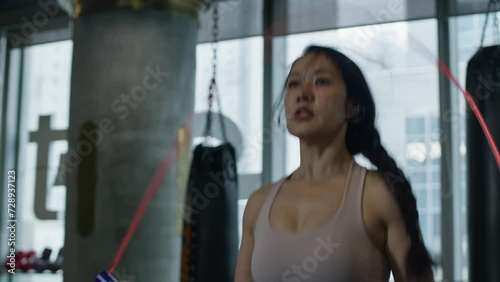Close up of female asiatic woman skipping jumping rope workout training routine indoor gym 