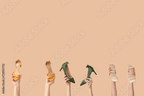 Women with stylish high-heeled shoes on beige background