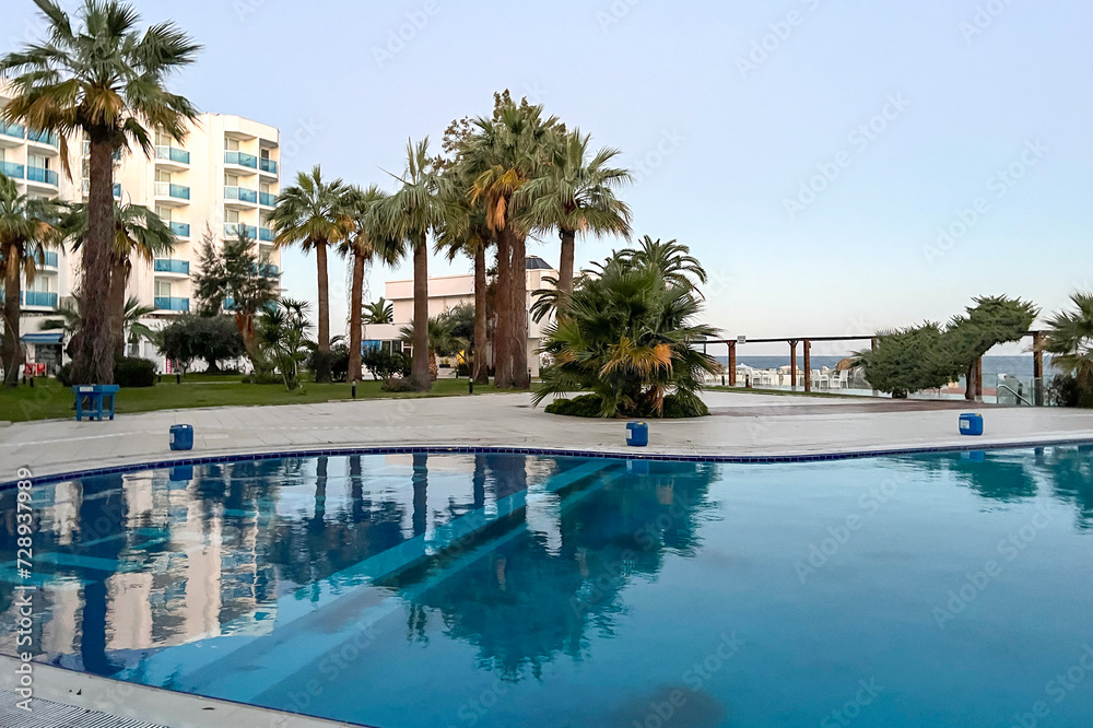 Beautiful swimming pool and palm trees in tropical hotel and resort on blue sky. Vacation and holiday concept