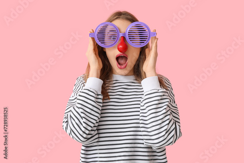 Beautiful young shocked woman in funny disguise on pink background. April Fools Day celebration photo